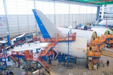 An airplane being assembled in a large aircraft manufacturing hangar.