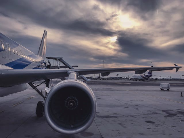 1. Modern commercial airplane at airport tarmac under dramatic cloudy sky.