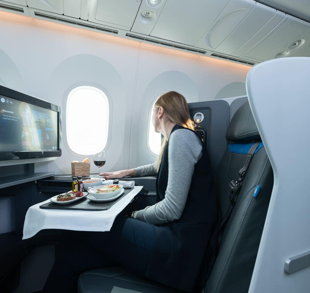 Comfortable first-class airplane cabin with gourmet meal and entertainment service.