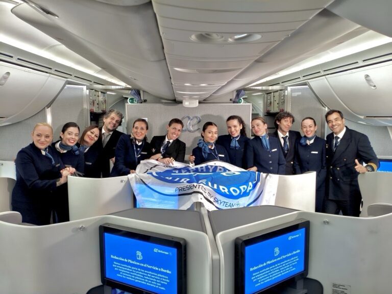 Flight crew celebrating onboard airline flight, smiling, holding a flag with Globalia branding.